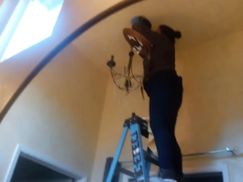 Electrician installing a chandelier in a Cottage Grove residence